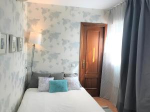 a bedroom with a white bed with a blue pillow at Casa Antón in Seville