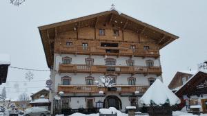 a large building with a wooden roof in the snow at Hotel Bechlwirt in Kirchberg in Tirol
