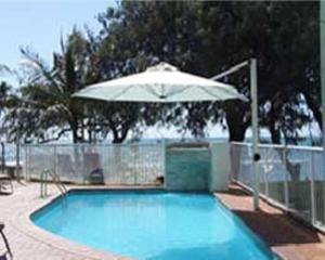 a swimming pool with an umbrella and an umbrella at Bargara Shoreline Apartments in Bargara