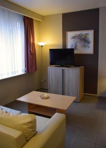 a living room with a couch and a table and a tv at City Apartments Antwerpen in Antwerp