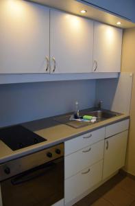 uma cozinha com armários brancos e um lavatório em City Apartments Antwerpen em Antuérpia