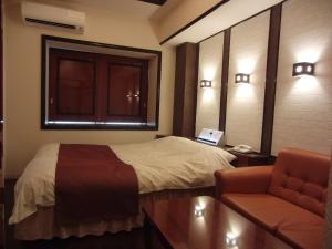 a bedroom with a bed and a chair and a window at Hotel Hyper Noah (Adult Only) in Sakai