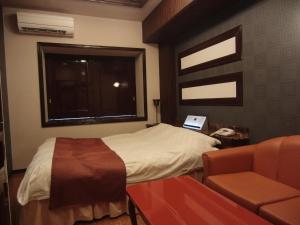 a bedroom with a bed and a chair and a window at Hotel Hyper Noah (Adult Only) in Sakai