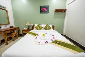 Un dormitorio con una cama blanca con una flor. en NKS Hotel, en Phnom Penh
