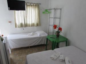 um quarto com duas camas e uma televisão e uma mesa em Pousada Sitio Costa Verde em Ubajara