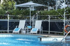 a swimming pool with chairs and an umbrella at Hotel Abner's in Riccione