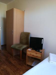 um quarto com uma cama, uma cadeira e uma televisão em Mátyás Szállás em Szombathely