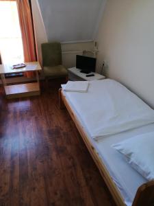 a bedroom with a bed and a chair and a window at Mátyás Szállás in Szombathely