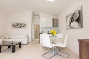 ein weißes Wohnzimmer mit einem Tisch und weißen Stühlen in der Unterkunft Eden Apartments in Zadar