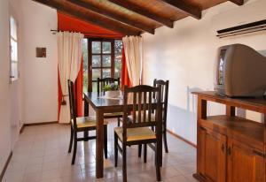 een eetkamer met een tafel en stoelen en een tv bij Cabañas y Lofts El Portal in Villa General Belgrano