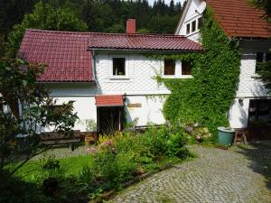 ein weißes Haus mit einem roten Dach und einem Garten in der Unterkunft Ferienwohnung Bauer Alter Hammer in Schmiedefeld am Rennsteig
