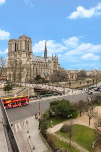 a view of the cathedral of notre dame with a double decker bus at Hotel Esmeralda in Paris