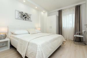 ein weißes Schlafzimmer mit einem Bett und einem Fenster in der Unterkunft Eden Apartments in Zadar