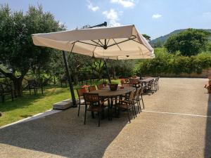 stół i krzesła z dużym białym parasolem w obiekcie Farm stay Agriturismo Casa Martelletto w mieście Serra San Quirico
