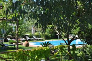 a person standing near a swimming pool in a garden at Hotel Tirrena Bike & Country Hotel in Portoferraio