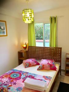 a bedroom with a bed with colorful pillows and a window at Maxi cosy appartement in Sainte-Anne