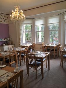 uma sala de jantar com mesas e cadeiras e um lustre em Coastal Waters (Hotel Barton) em Torquay
