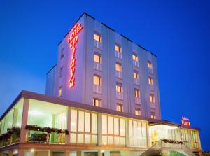a tall building with a neon sign on it at Hotel Playa in Bibione