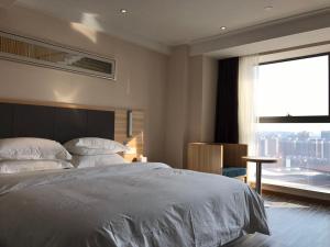 Postel nebo postele na pokoji v ubytování Hotel Pomelo Premier 西柚臻选武昌站酒店