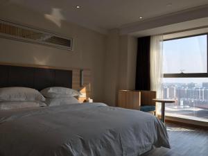 Rúm í herbergi á Hotel Pomelo Premier 西柚臻选武昌站酒店