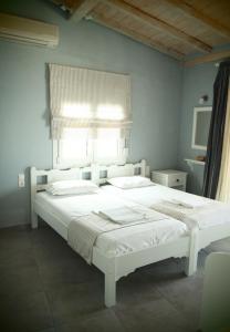 a white bed in a room with a window at Vetti Rooms in Skiathos