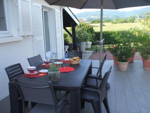 einem schwarzen Tisch mit Stühlen und einem Sonnenschirm auf einer Terrasse in der Unterkunft Les Varennes in Saint-Alban-les-Eaux