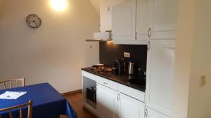 a kitchen with white cabinets and a table and a clock at Vakantiehuis Limburg - Landgraaf in Landgraaf