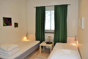 Habitación con 2 camas y ventana con cortinas verdes. en Södra Bergets Vandrarhem en Sundsvall