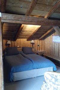 Schlafzimmer mit blauem Bett und Holzdecken in der Unterkunft Chambre d'Hôtes La ferme d'en bas in Samoëns