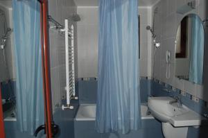 a bathroom with a blue shower curtain and a sink at Hotel Kibella in Sofia