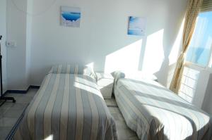 two beds in a room with a window at Apartamento Mar Puerto Sherry in El Puerto de Santa María