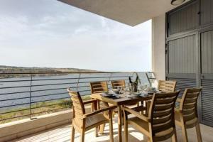 a wooden table and chairs on a balcony at Water's Edge Apartment in St Paul's Bay