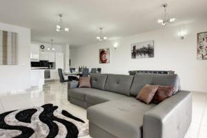 sala de estar con sofá gris y alfombra en Water's Edge Apartment en St Paul's Bay