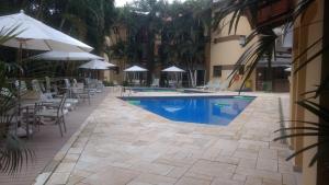 a swimming pool with chairs and umbrellas next to a building at Riviera Green in Riviera de São Lourenço