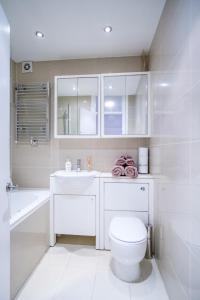 a white bathroom with a toilet and a sink at Quality Stylish Flat in Russell Square in London