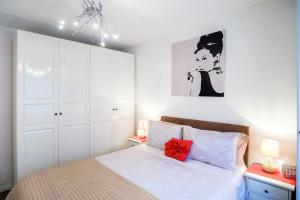 a bedroom with a bed with white cabinets and red pillows at Quality Stylish Flat in Russell Square in London
