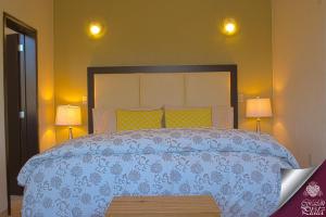 een slaapkamer met een bed met een blauw dekbed en 2 lampen bij Casa Corazon de Plata Suites in Guanajuato
