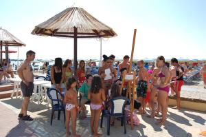 Bikini Tropicana Family Hotel في ليدو دي سافيو: مجموعة من الناس تقف على الشاطئ