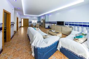 Habitación grande con varios sofás y TV. en Casa Pescadores de Vallterra en El Palmar