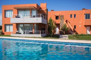 a house with a swimming pool in front of a building at Lomas del Real Aparthotel in Colonia del Sacramento