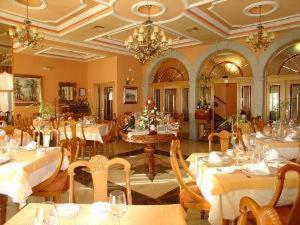 a dining room with tables and chairs and a chandelier at Hotel Santa Teresa in Ávila
