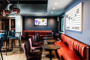 een restaurant met rode leren stoelen en een tv aan de muur bij Malmaison Brighton in Brighton & Hove