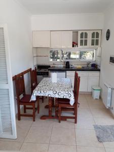 una cocina con mesa y sillas y una cocina con armarios blancos. en Complejo Sol&Luna en Villa Ventana