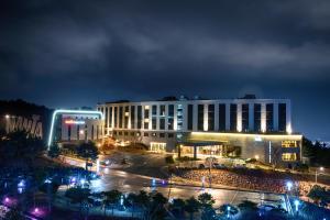 un grand bâtiment avec des lumières devant lui la nuit dans l'établissement Hotel Nanta Jeju, à Jeju