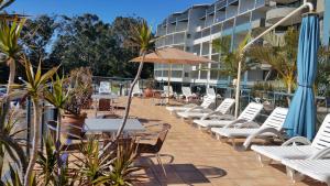 une rangée de chaises, de tables et de parasols blancs dans l'établissement Casablanca Penthouse Loft - Landmark 518, à Nelson Bay