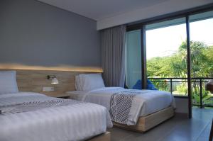 a hotel room with two beds and a balcony at Padang-Padang Inn in Uluwatu