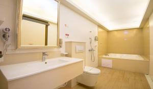 a bathroom with a sink and a tub and a toilet at M Garden Business Hotel in Tainan