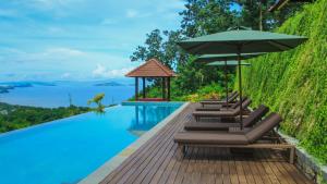 a swimming pool with lounge chairs and an umbrella at Villa Domanik in Labuan Bajo