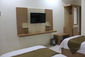 a room with two beds and a tv on the wall at Morse Guest house in Malang