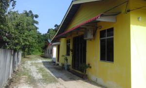 uma casa amarela com uma cerca em frente em NUE Guesthouse em Kota Bharu